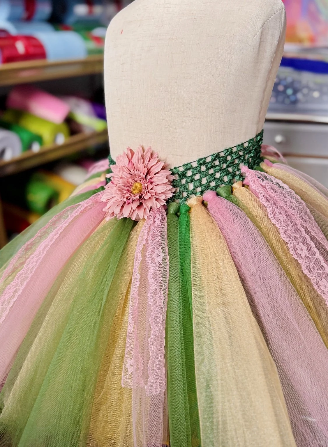 Handmade pastel pink, yellow, and green tutu with a floral waistband, displayed on a mannequin.