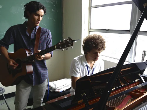 Songwriters collaborating at piano and guitar
