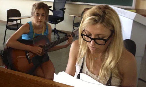 Two songwriters working through a new song with guitar