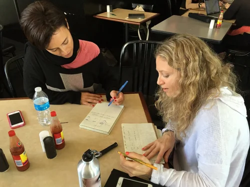 Two lyricists writing at a table