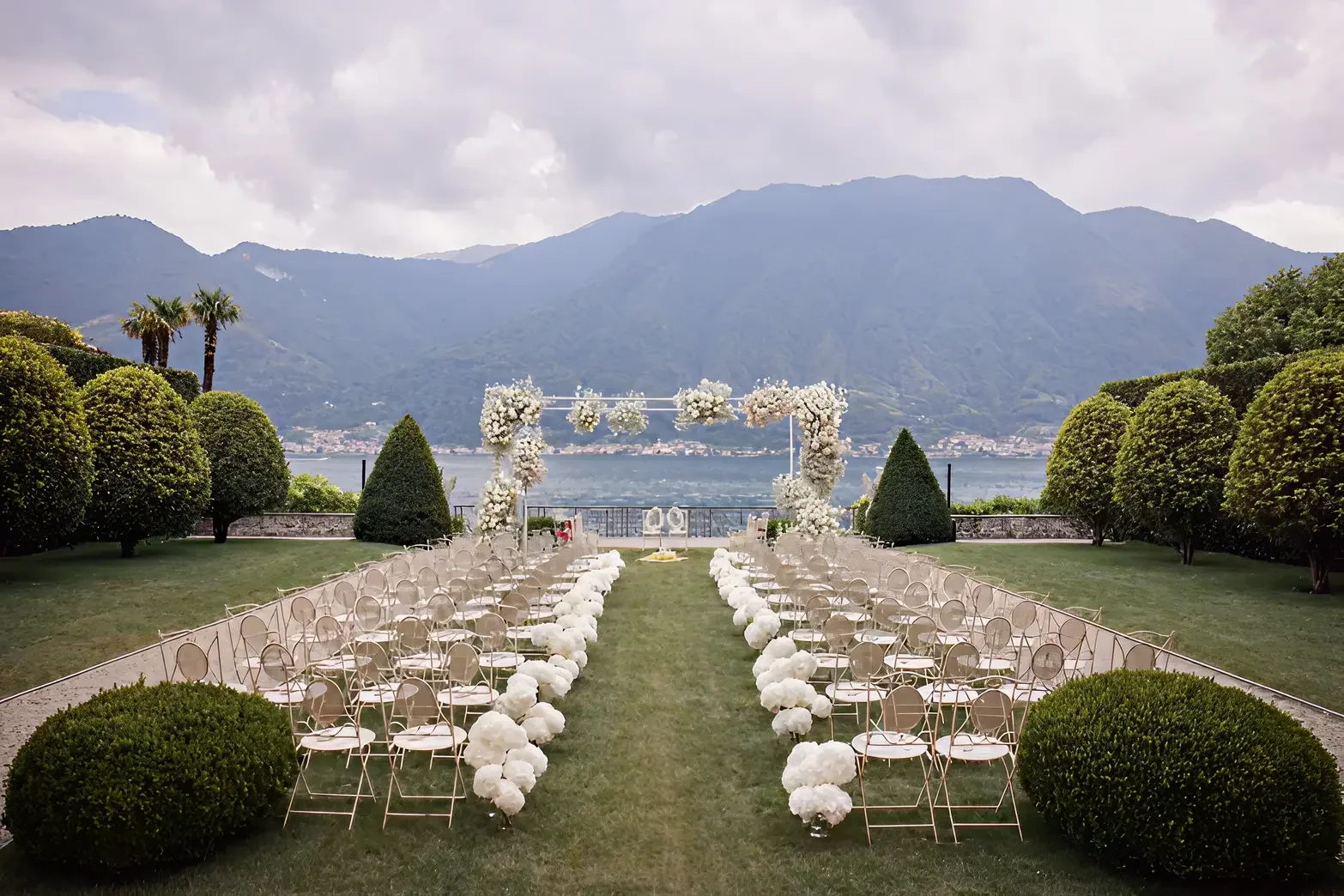 Outdoor wedding ceremony with floral arch overlooking a lake and mountains