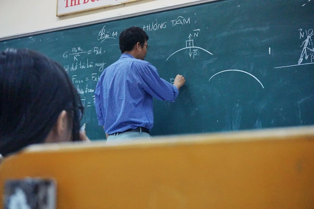 A teacher writing equations on a classroom chalkboard