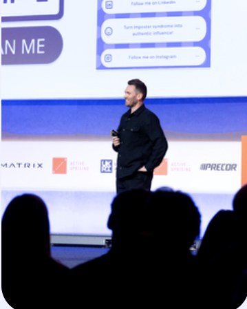 Dean Leak speaking on stage in front of a conference audience