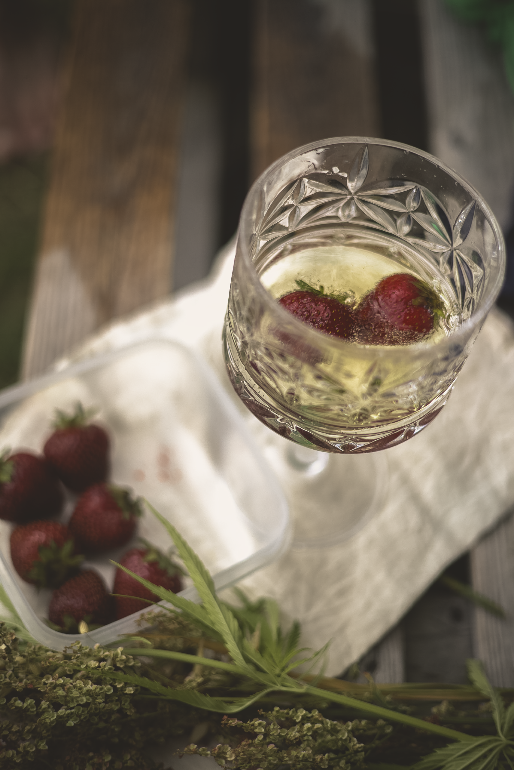 Sparkling wine with strawberries beside a linen cloth and meadow flowers