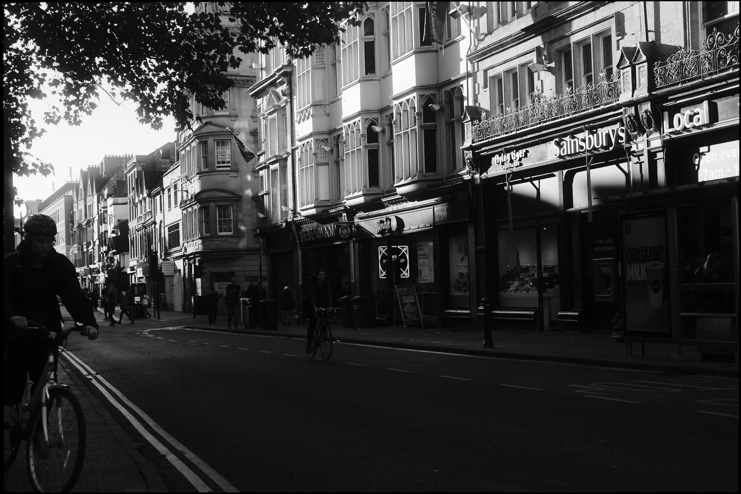 Black and white street scene on Cornmarket with a cyclist silhouetted against shopfronts.