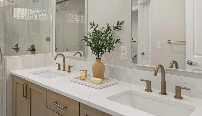Double undermount sinks with a quartz countertop, shaker vanity, and brushed brass faucets for Bellevue WA bathroom remodel