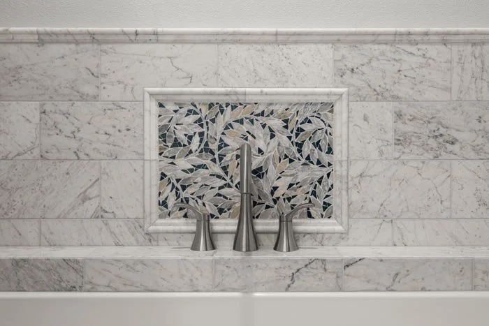 Marble tile tub surround with mosaic accent and wall-mounted fixtures—custom tilework in a Bellevue, WA bathroom remodel