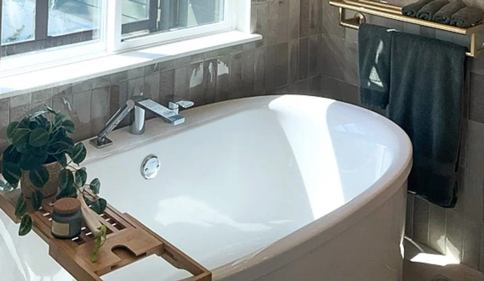 Freestanding soaking tub with tray by a sunny window for primary bathroom remodel in Tacoma, WA