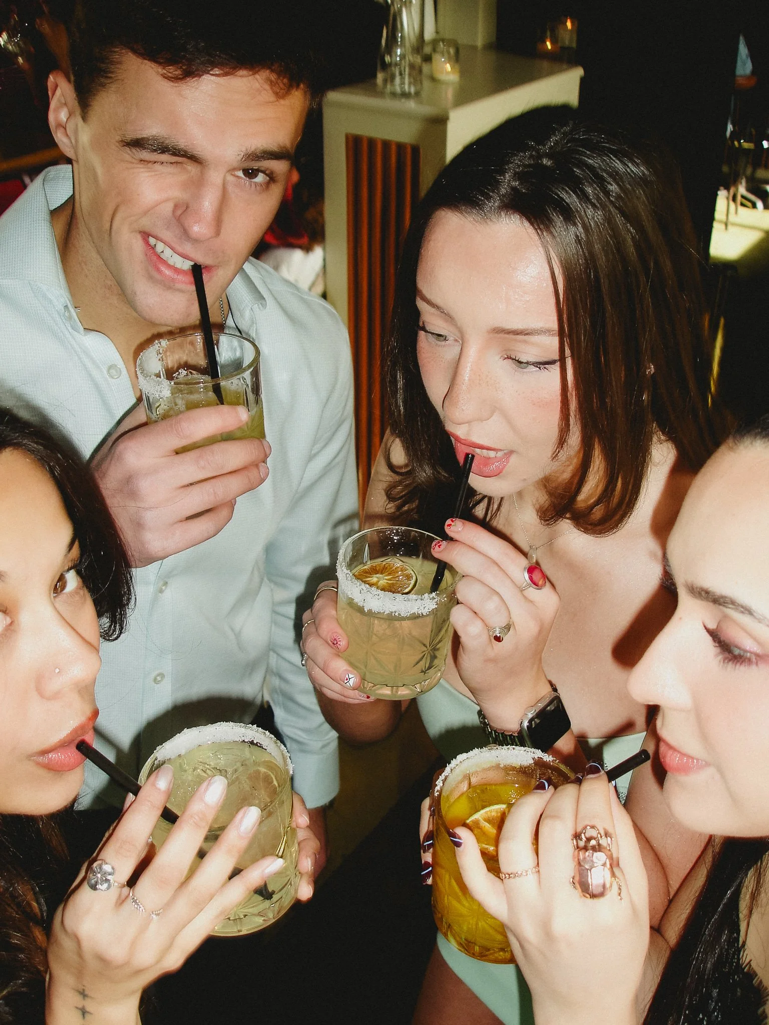 Three women and a man drinking margaritas with salt rims in a circle at Avendia