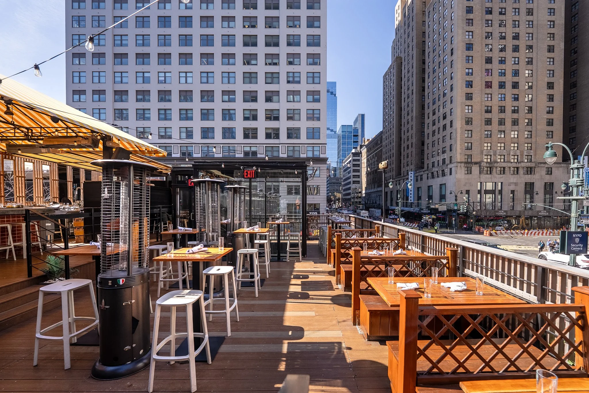 Seating area on Avenida's rooftop with large buildings on 8th Ave in the background