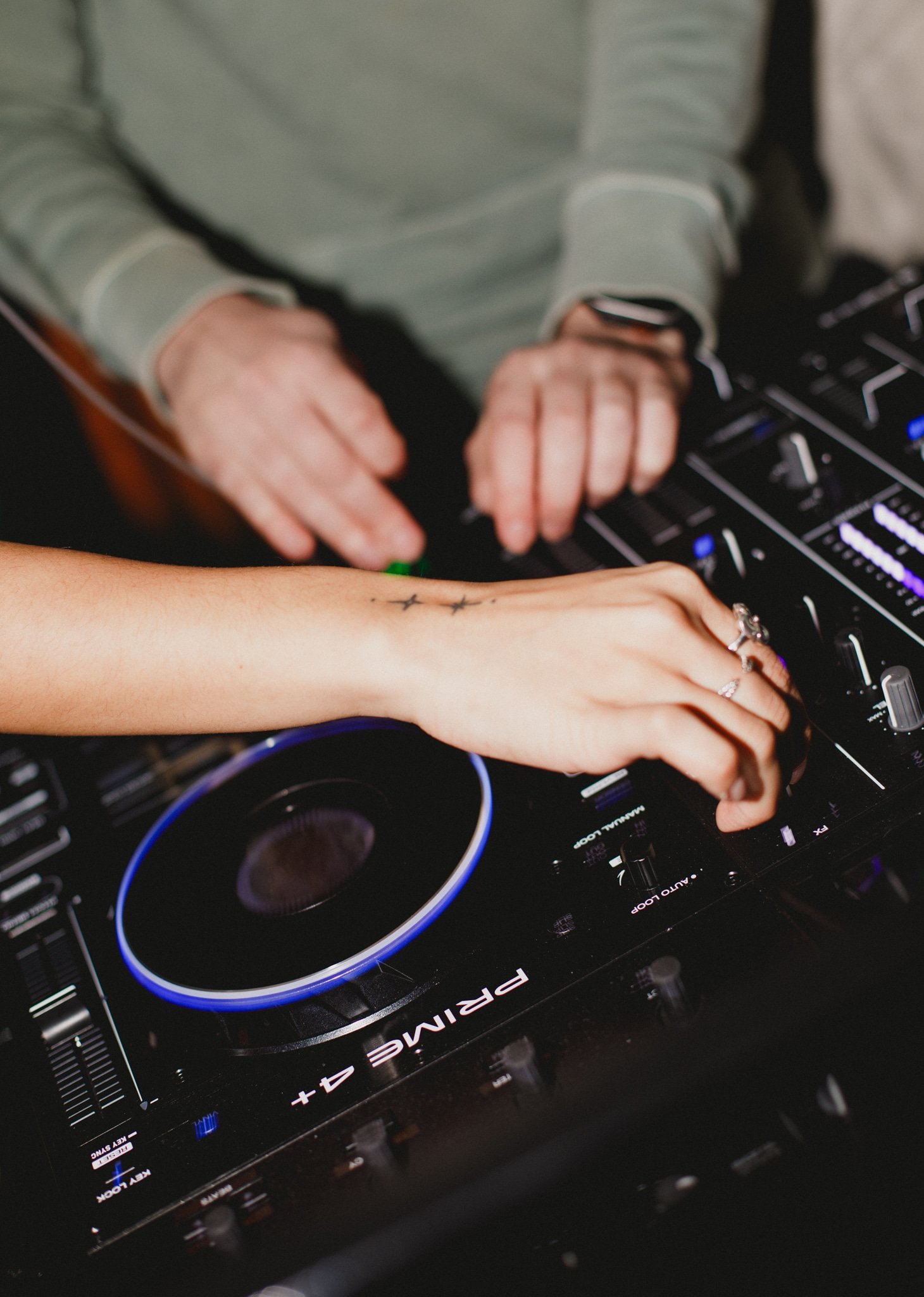 close up of dj decks with hands adjusting and using the turntable
