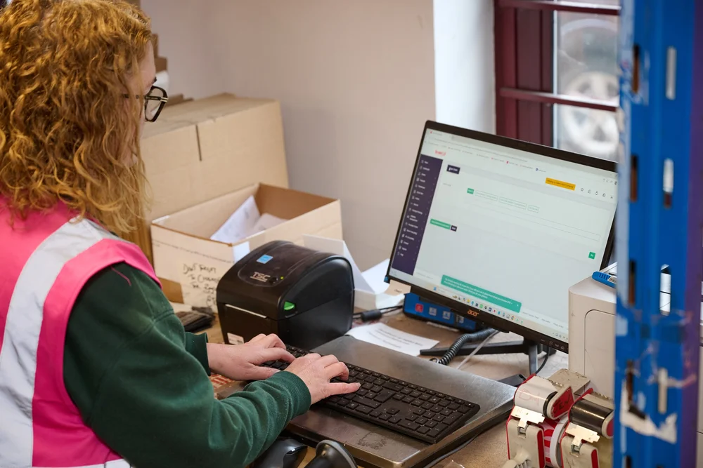 Packer at a Scale 3PL packing desk processing orders