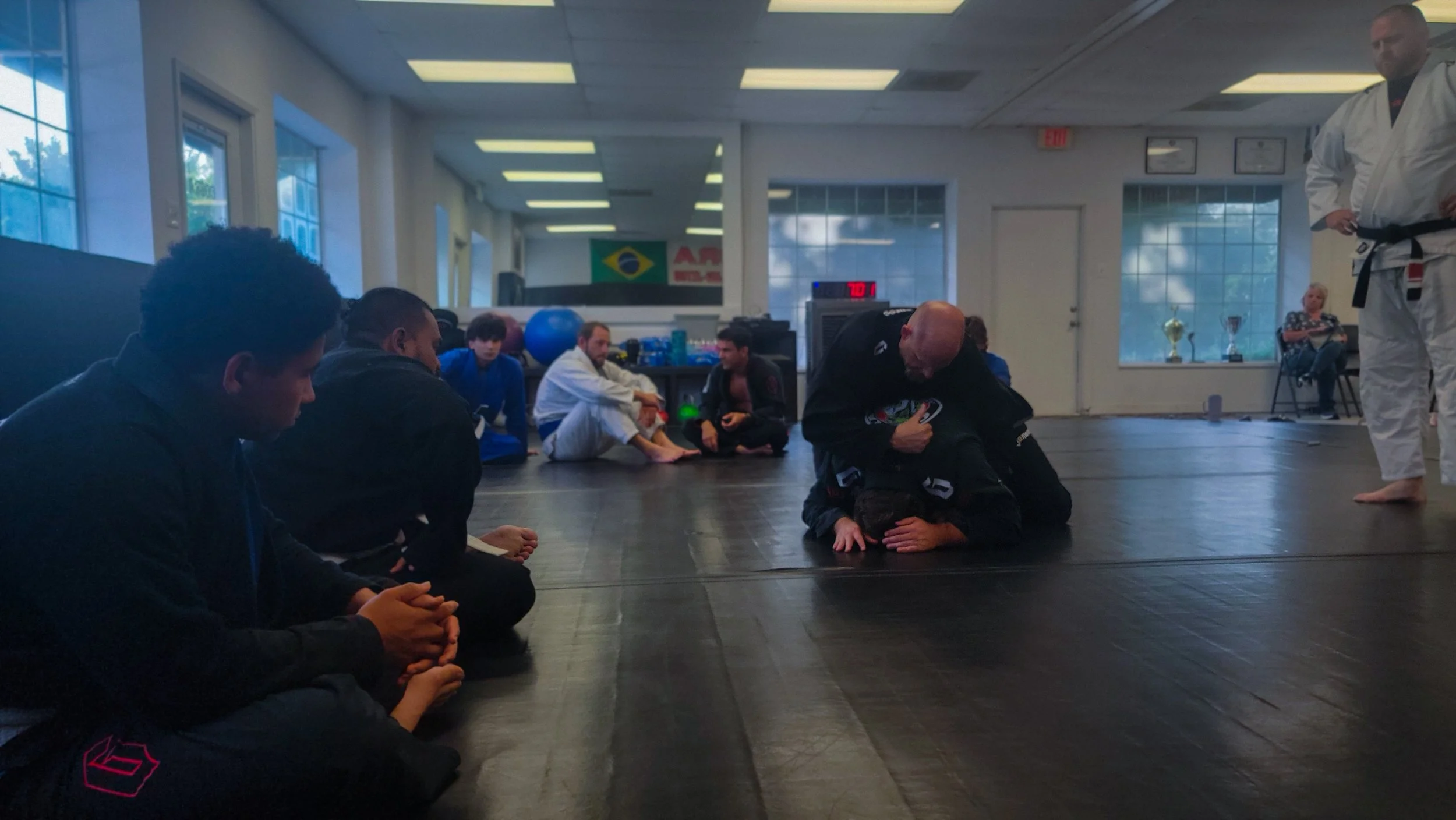 Students watching a technique being demonstrated on the mat at Cobra BJJ Mansfield