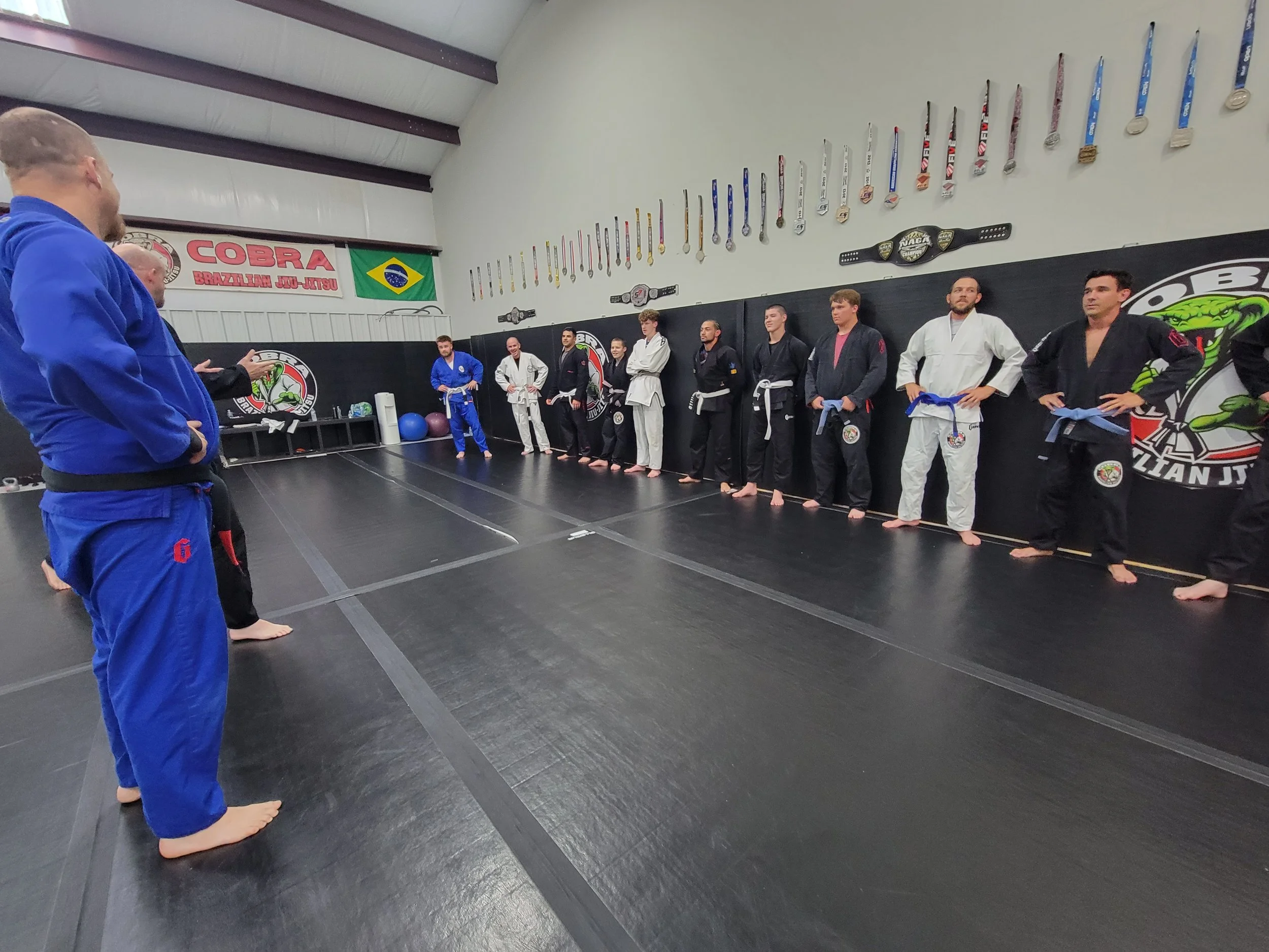 Students lined up along the wall listening to the instructor at Cobra BJJ Mansfield