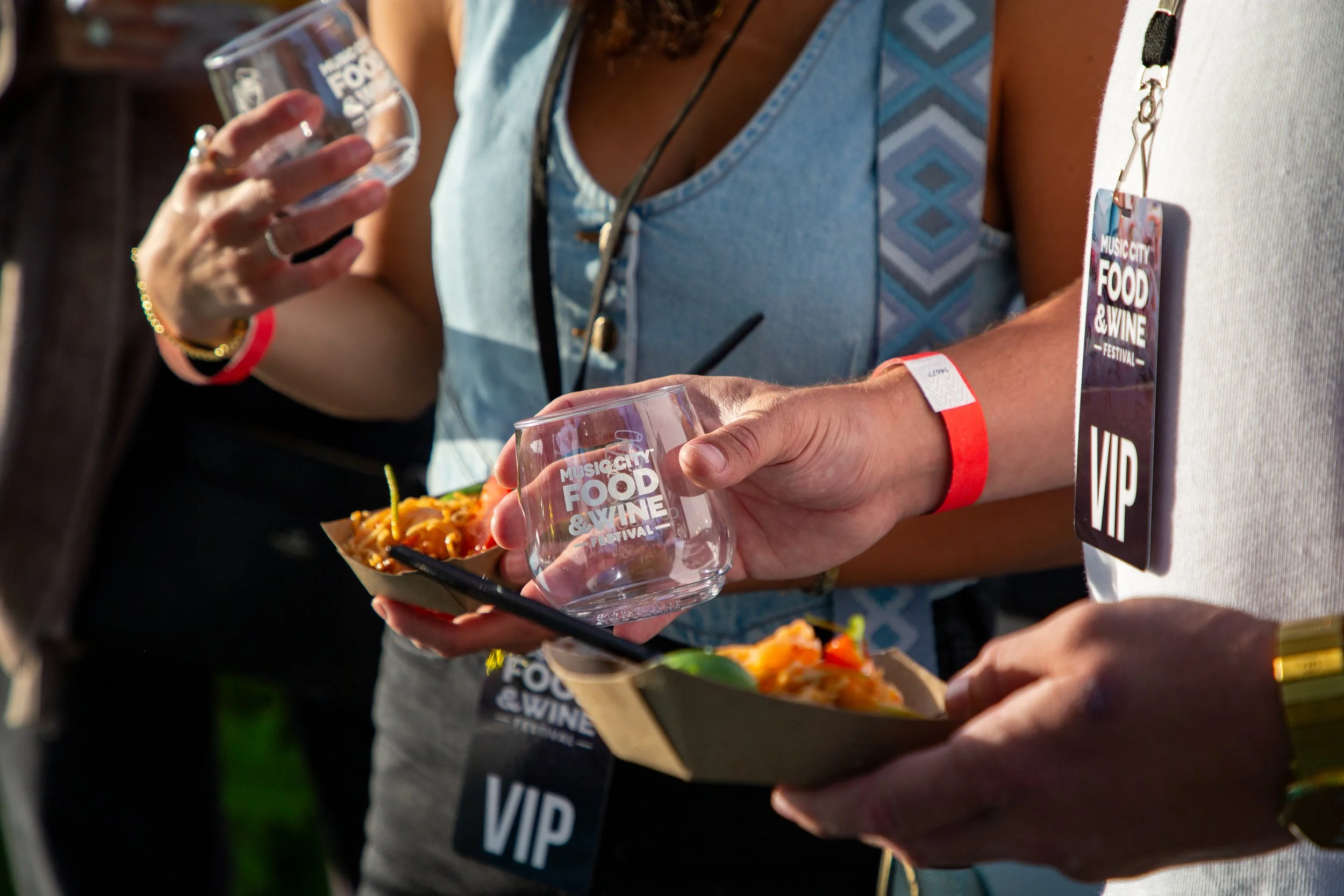 Attendees holding wine glasses at a VIP event.