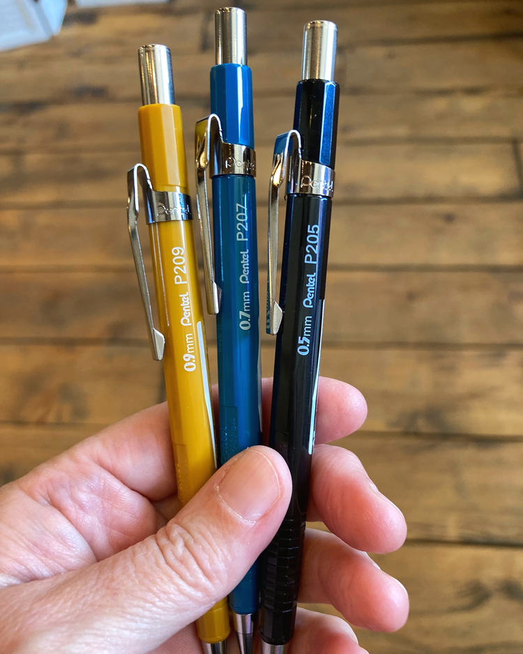 A hand holding three mechanical pencils