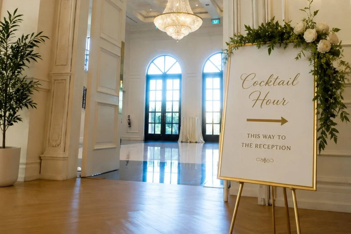 Wedding directional signage guiding guests from cocktail hour to the reception at an elegant indoor venue.