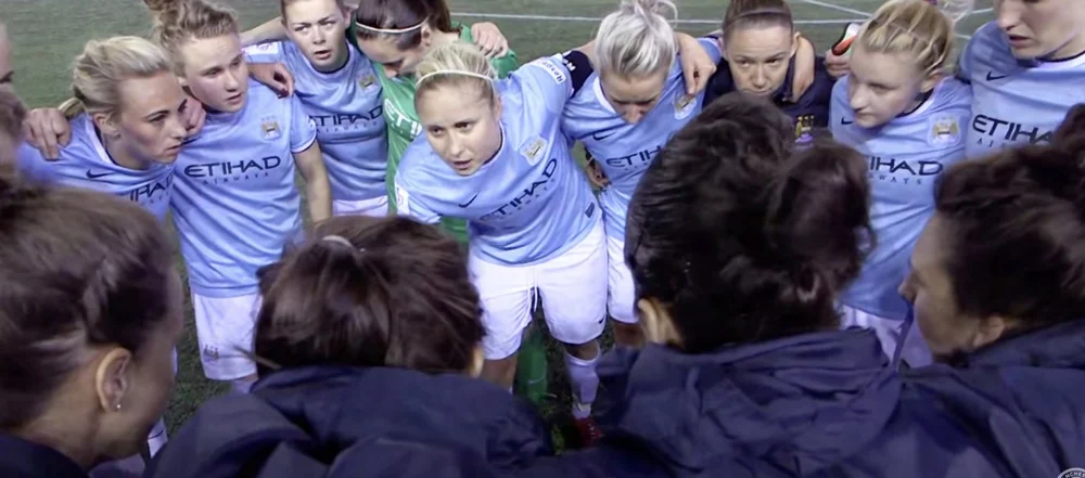 Women footballers in a team huddle