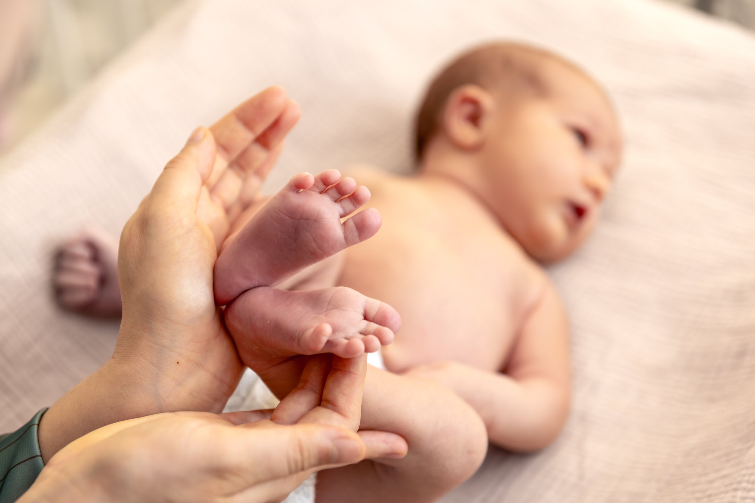 Chiropractor gently holding a newborn baby’s feet