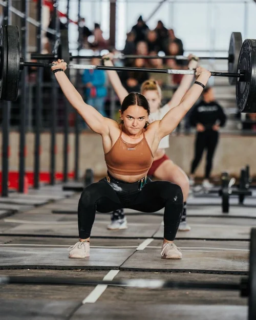 Teen athlete holding an overhead squat at a fitness competition