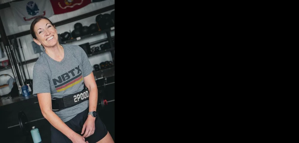 Member laughing between sets in an NBTX shirt and lifting belt