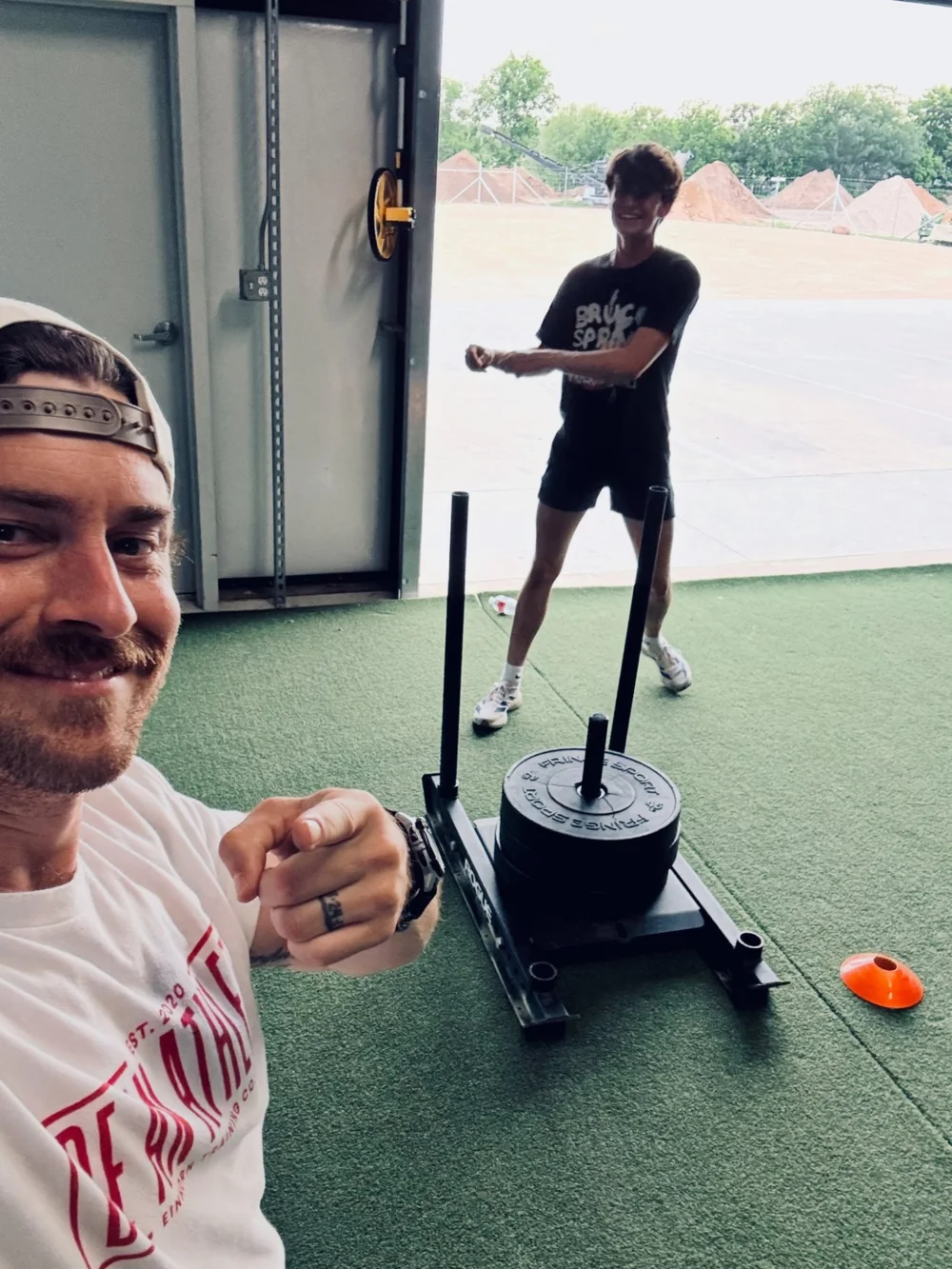 Coach Grant Reber coaching a young athlete through a sled push at Einhorn Training Co. in New Braunfels