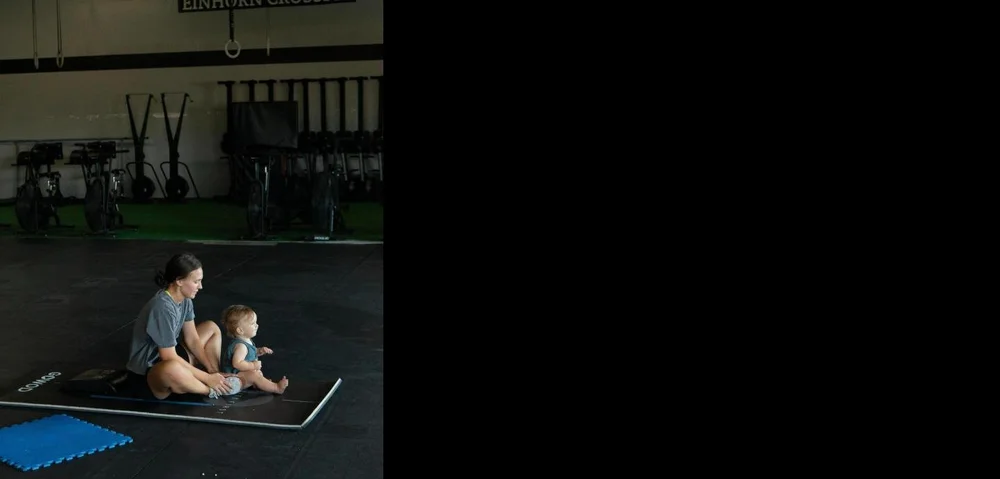 Mom stretching on a mat with her baby at the gym in New Braunfels