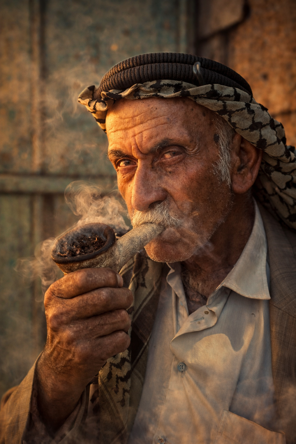 An older man smoking a pipe in warm light