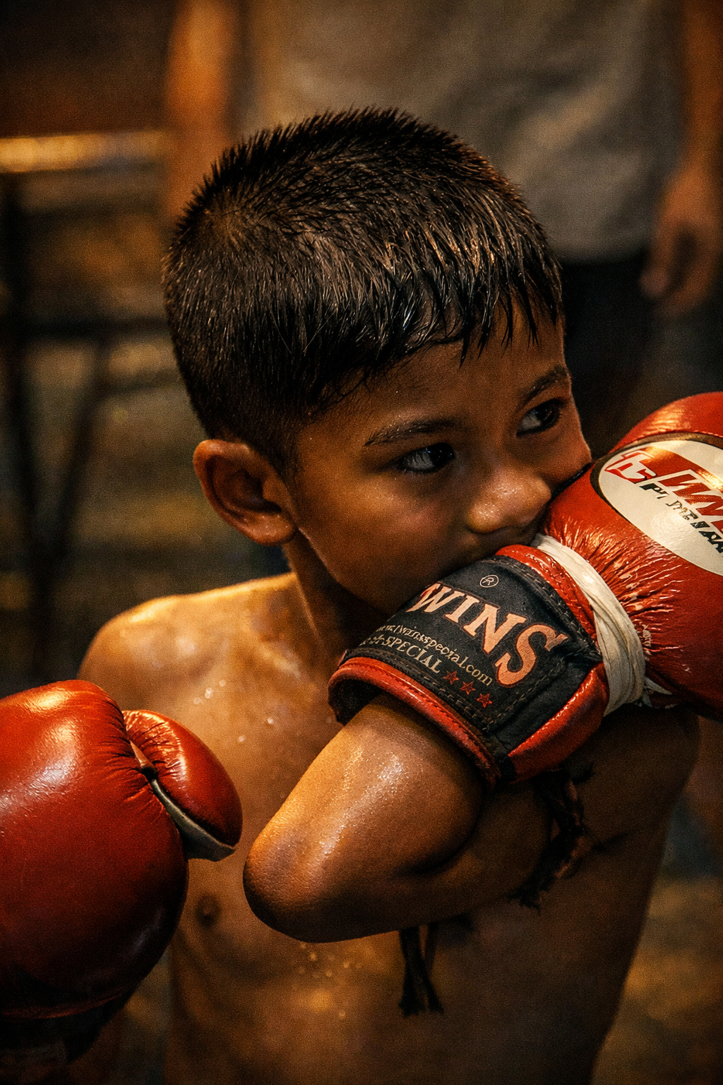 A young boxer holding red gloves close to his face
