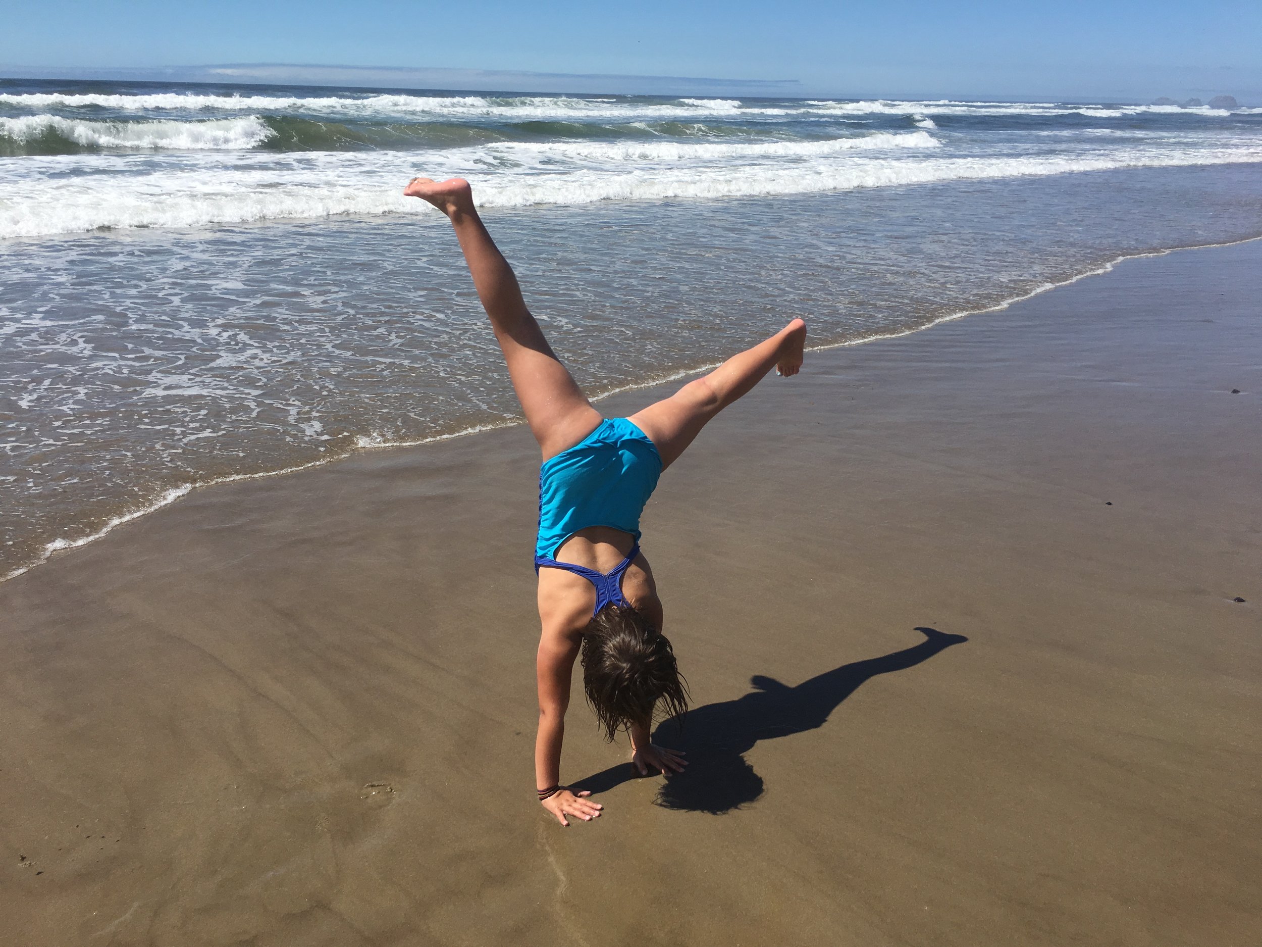 A photo of a child cartwheeling on the beach