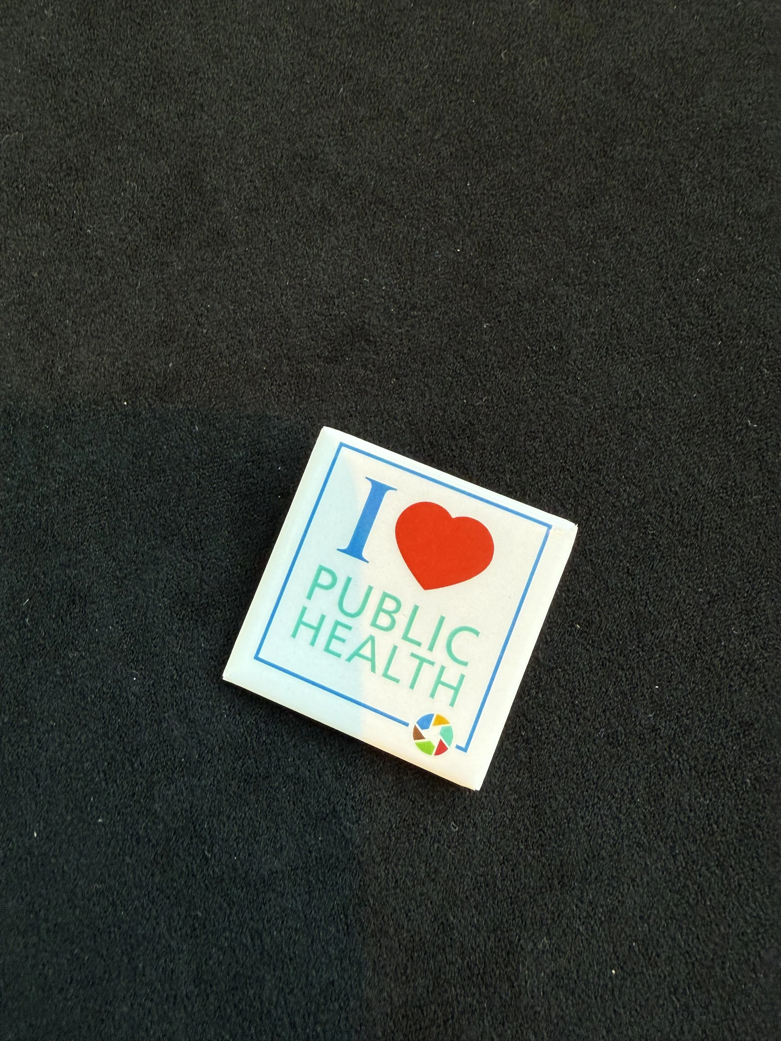 A photo of a pin that says I heart public health