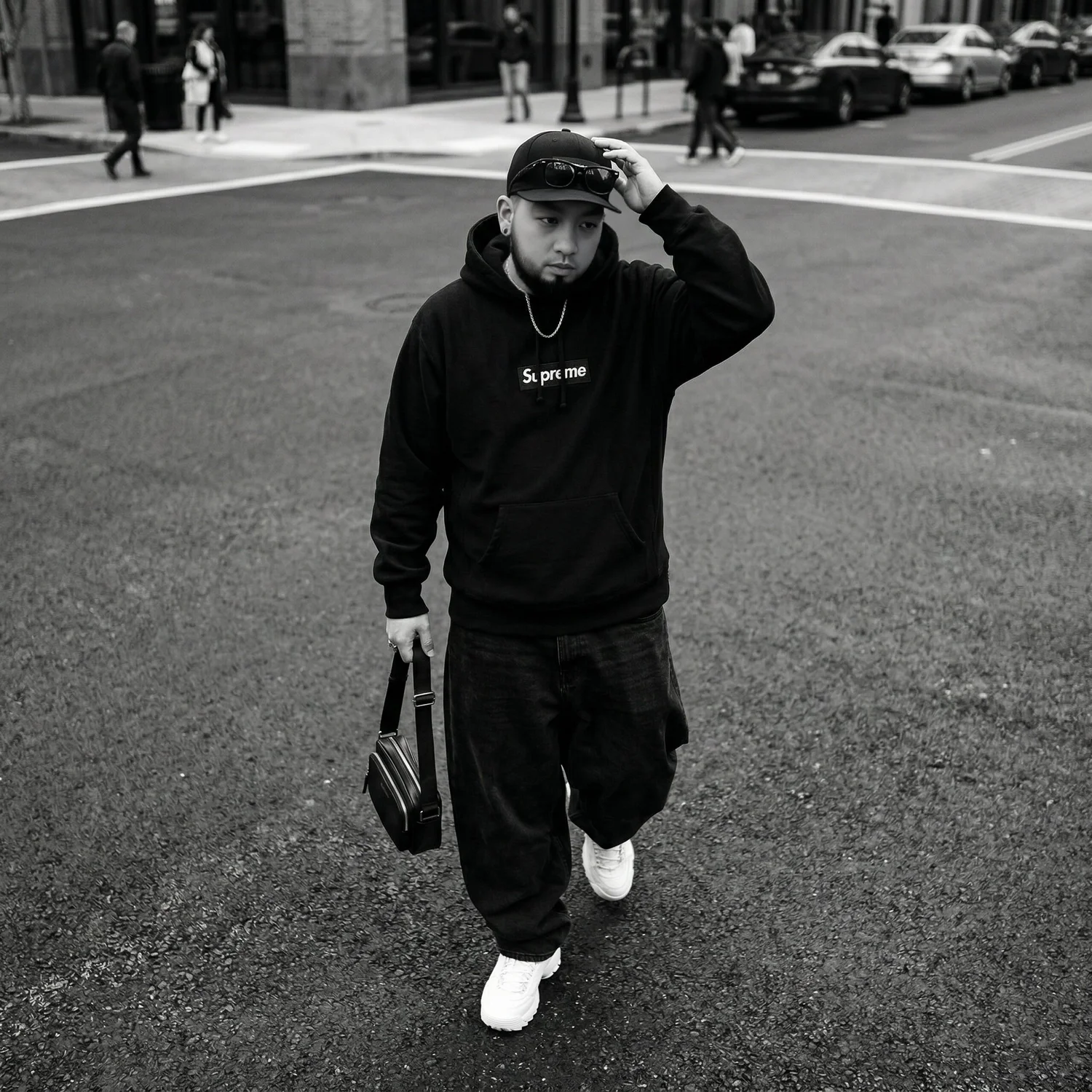 Paul Vu, Philadelphia creative director and graphic designer, crossing a city street in a black hoodie and cap