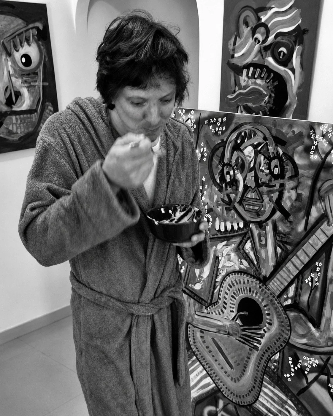 Kristian Marr eating breakfast in a dressing gown in front of three of his own large paintings.