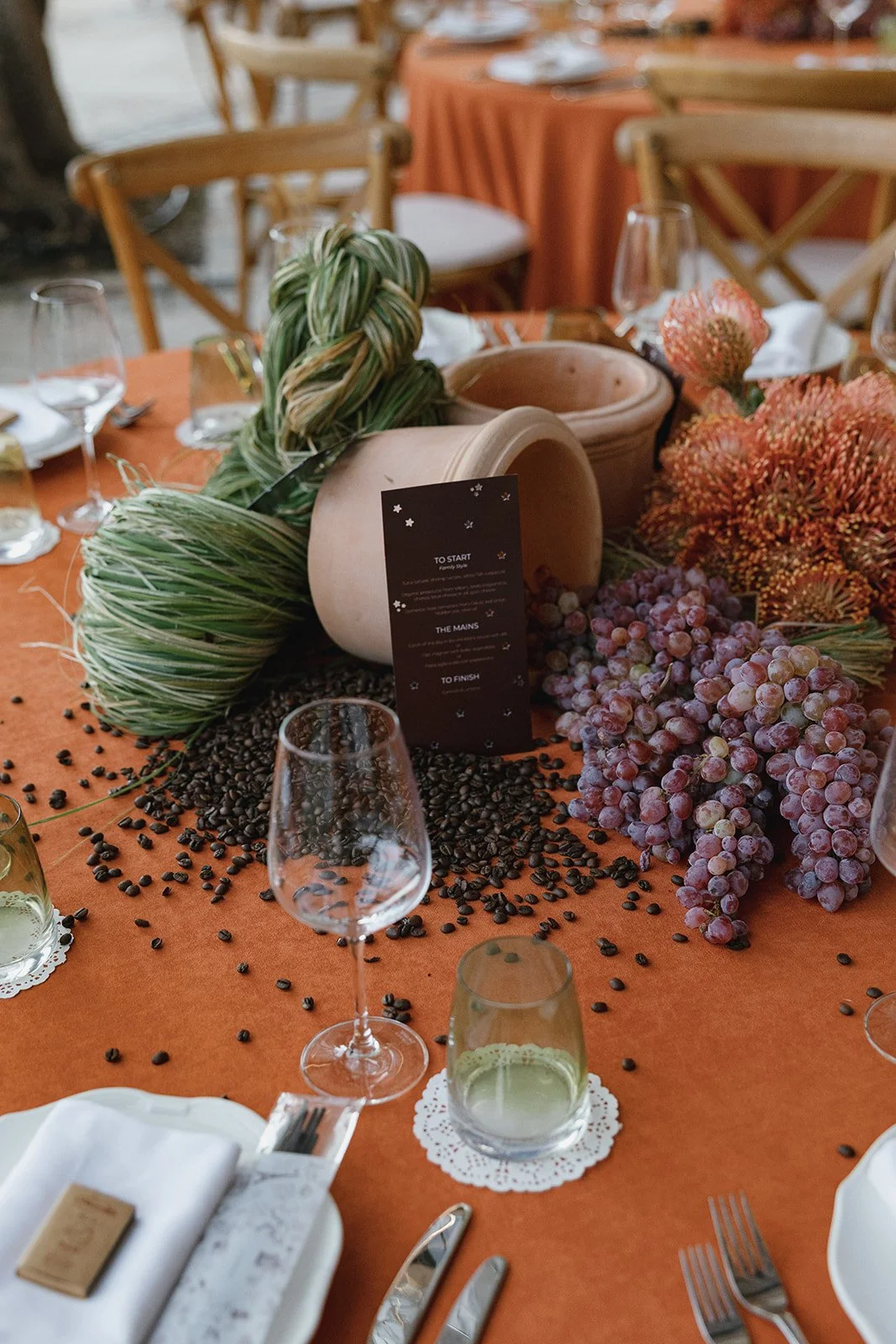 Long communal dining table set under lemon trees with terracotta and lace details for welcome dinner