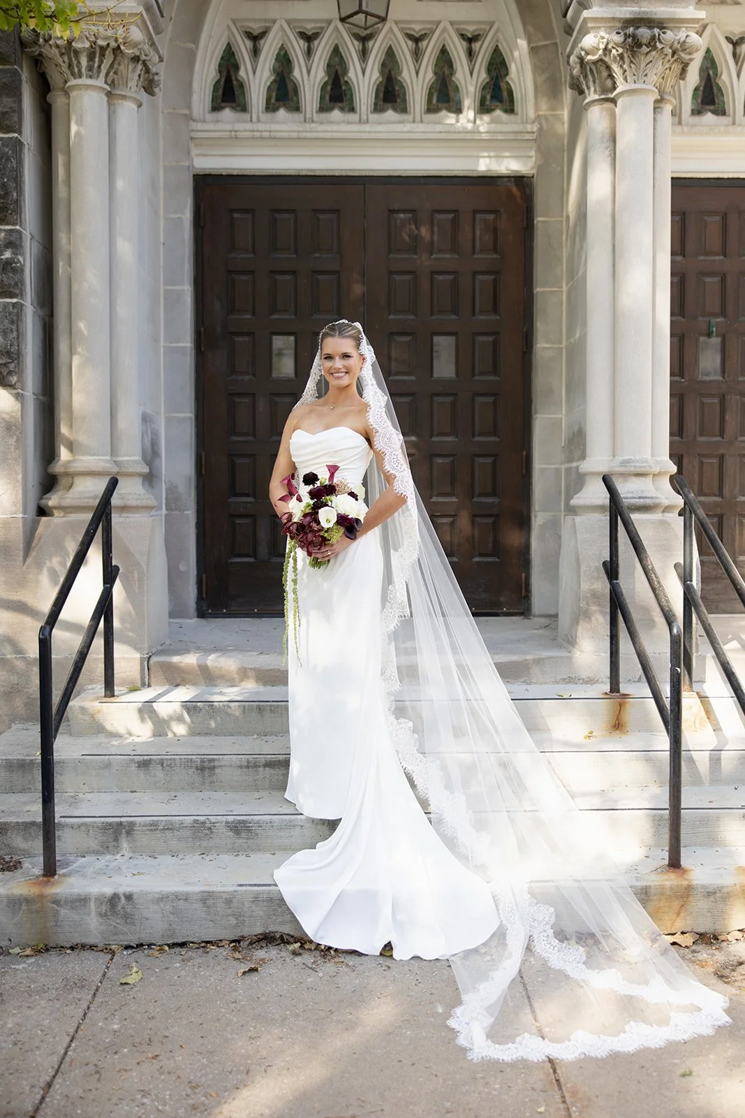 Bride with a burgundy and ivory bouquet on the church steps, florals by Hydrangea Bloom, photographed by Madisen Timp Weddings