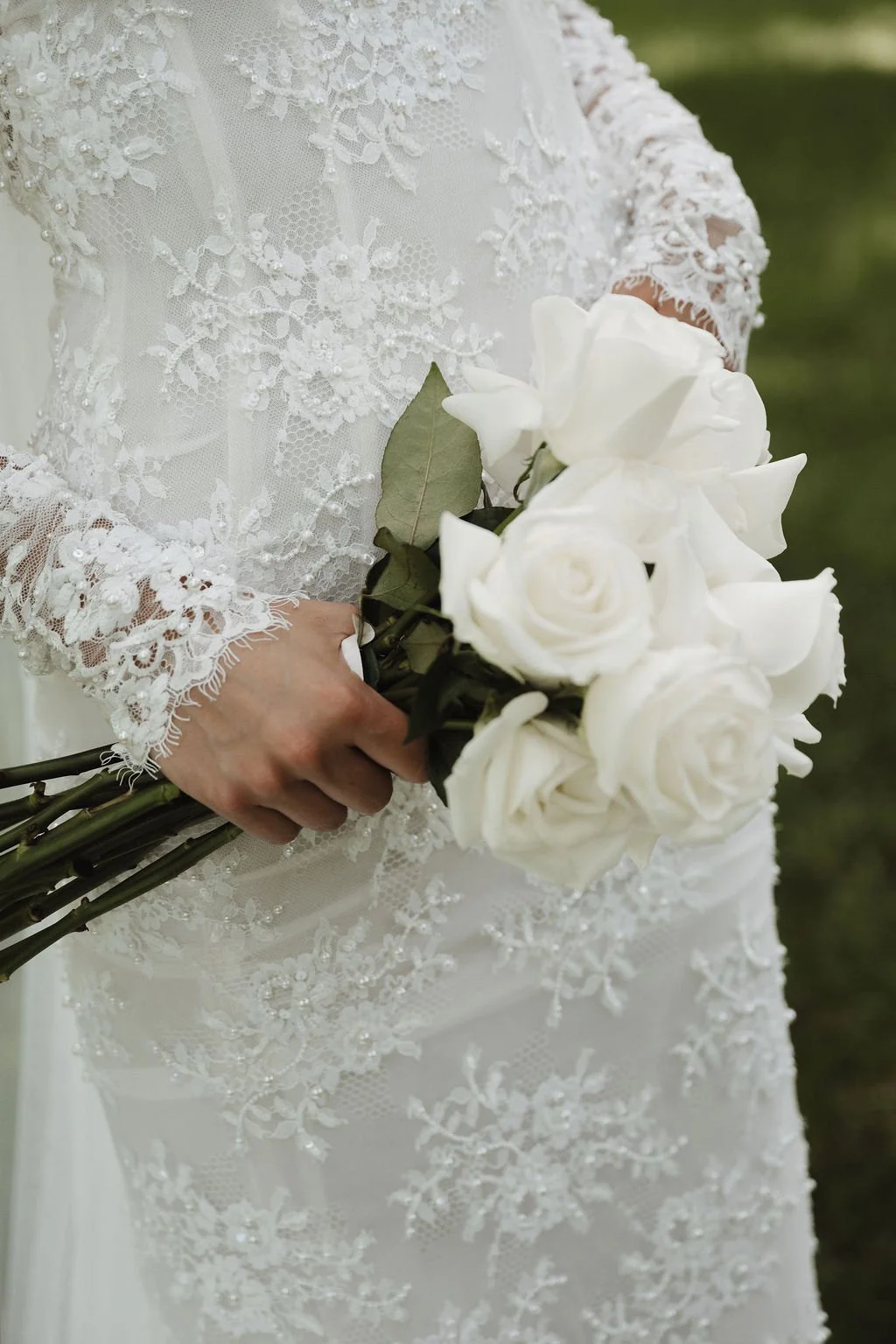 White rose bouquet held against a lace gown, florals by Hydrangea Bloom, photographed by Shelby Sawyer Photography