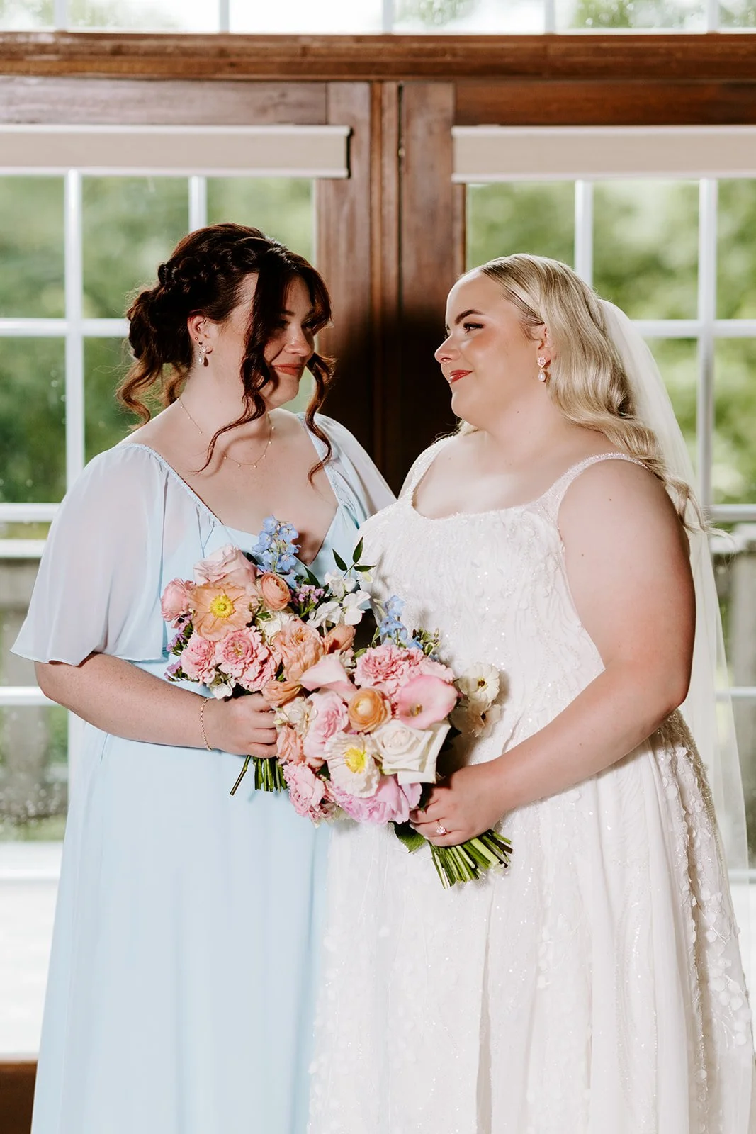 Bride and bridesmaid holding their bouquets, florals by Hydrangea Bloom, photographed by Karly Ellis Photography