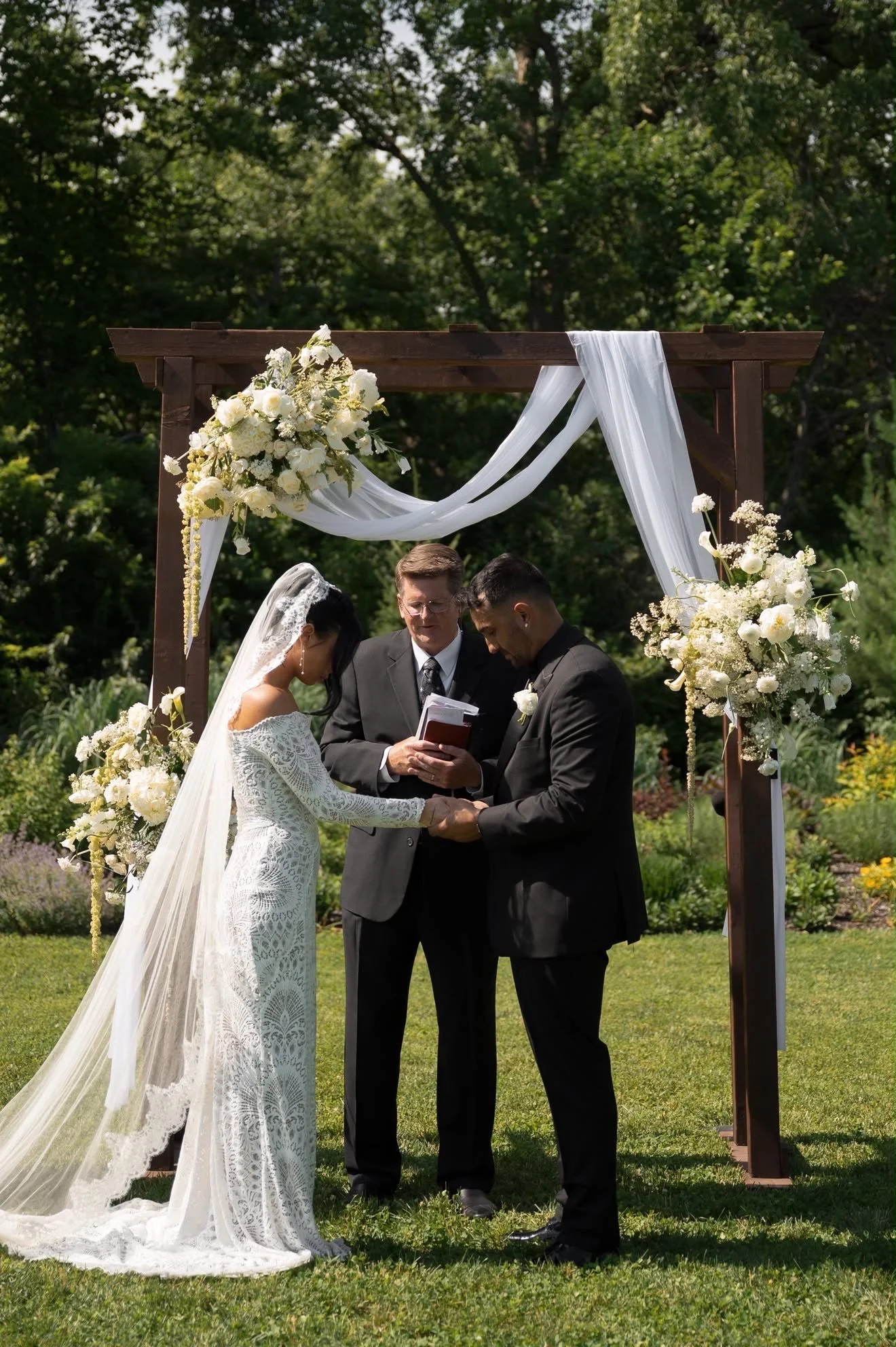 Couple exchanging vows beneath the floral arch, florals by Hydrangea Bloom, photographed by Hayley Dolson Photography
