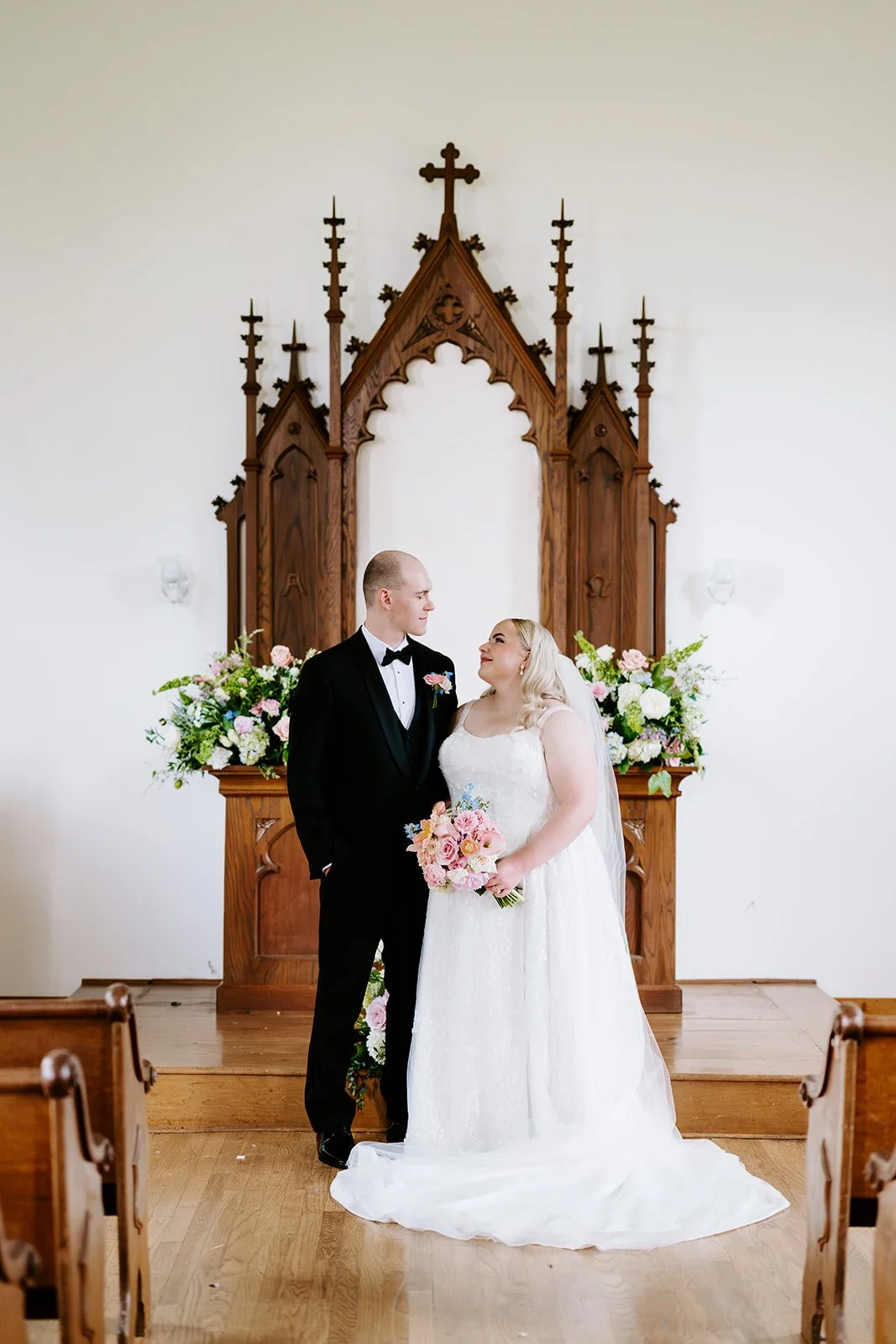 Couple at the chapel altar framed by florals, florals by Hydrangea Bloom, photographed by Karly Ellis Photography