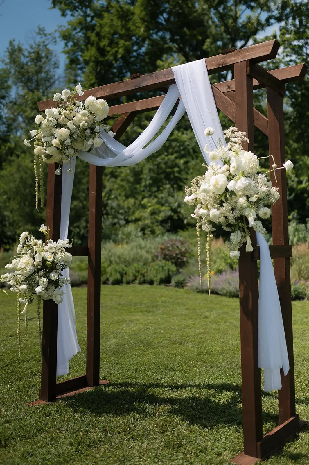 Wooden ceremony arch with white florals and draped chiffon, florals by Hydrangea Bloom, photographed by Hayley Dolson Photography