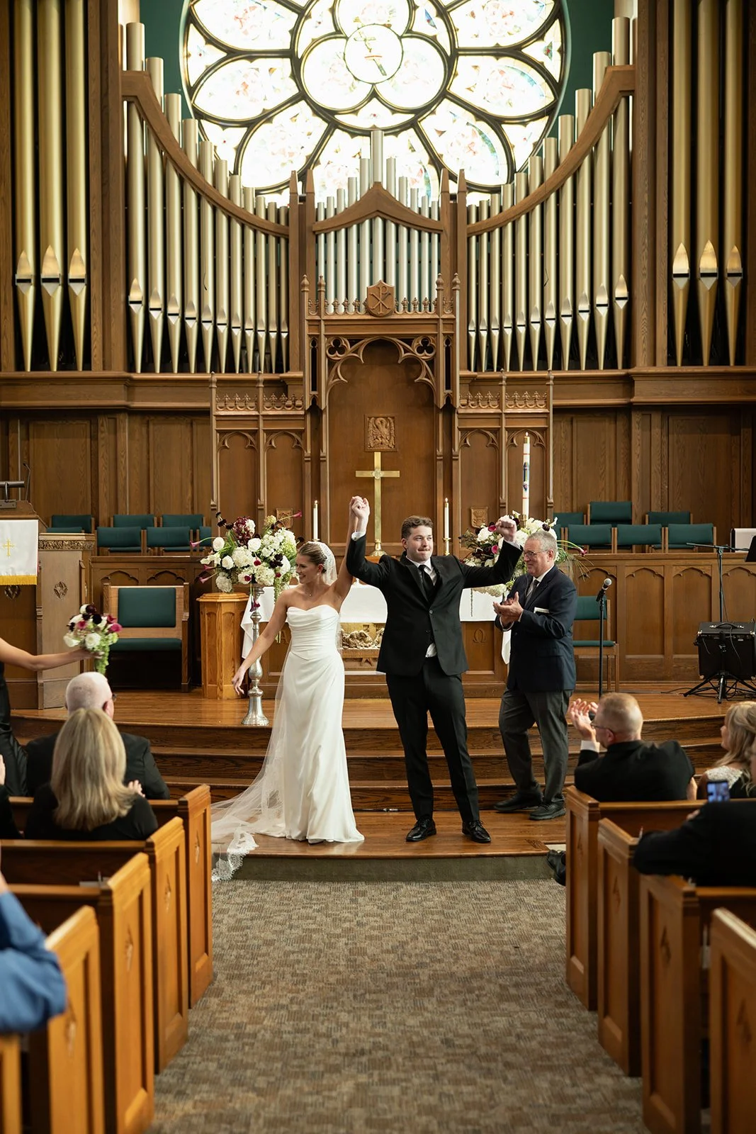 Couple at the altar with the ceremony florals, beneath the organ, florals by Hydrangea Bloom, photographed by Madisen Timp Weddings