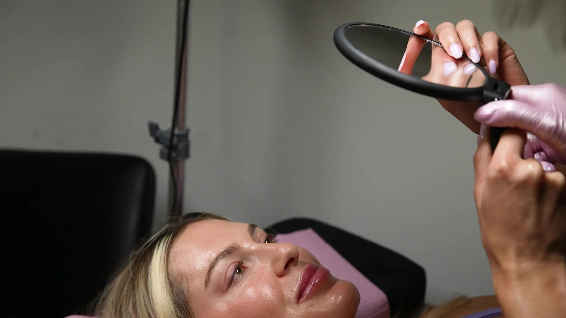 Clienta mirándose en un espejo después de su tratamiento