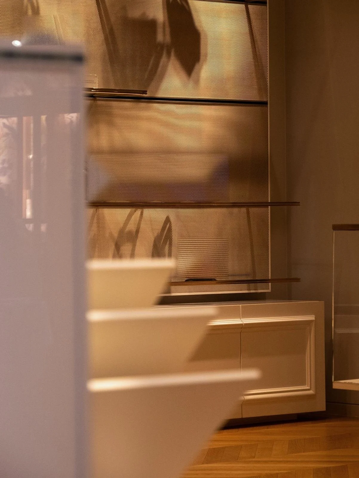 Bronze mesh display shelves and white plinths in a softly lit luxury boutique