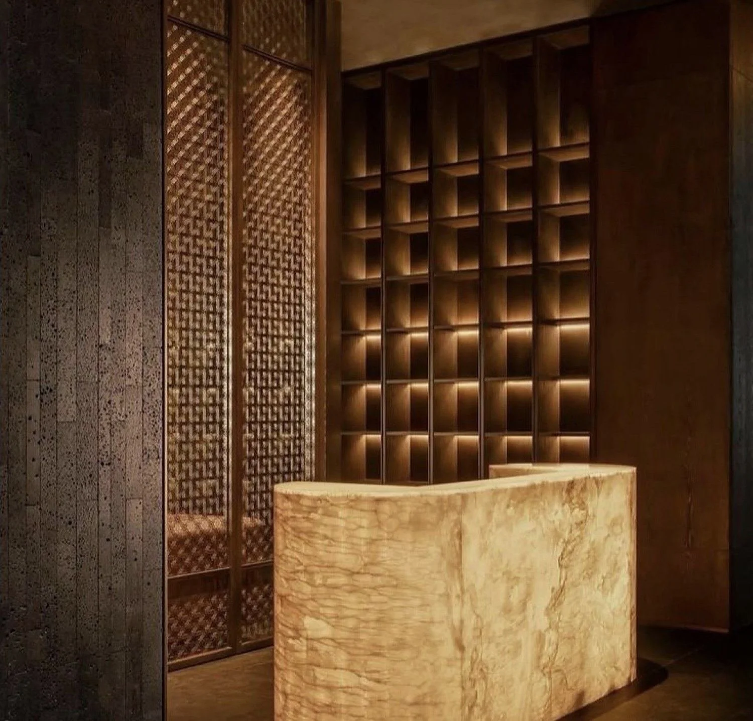 Backlit onyx reception counter in front of softly lit timber shelving