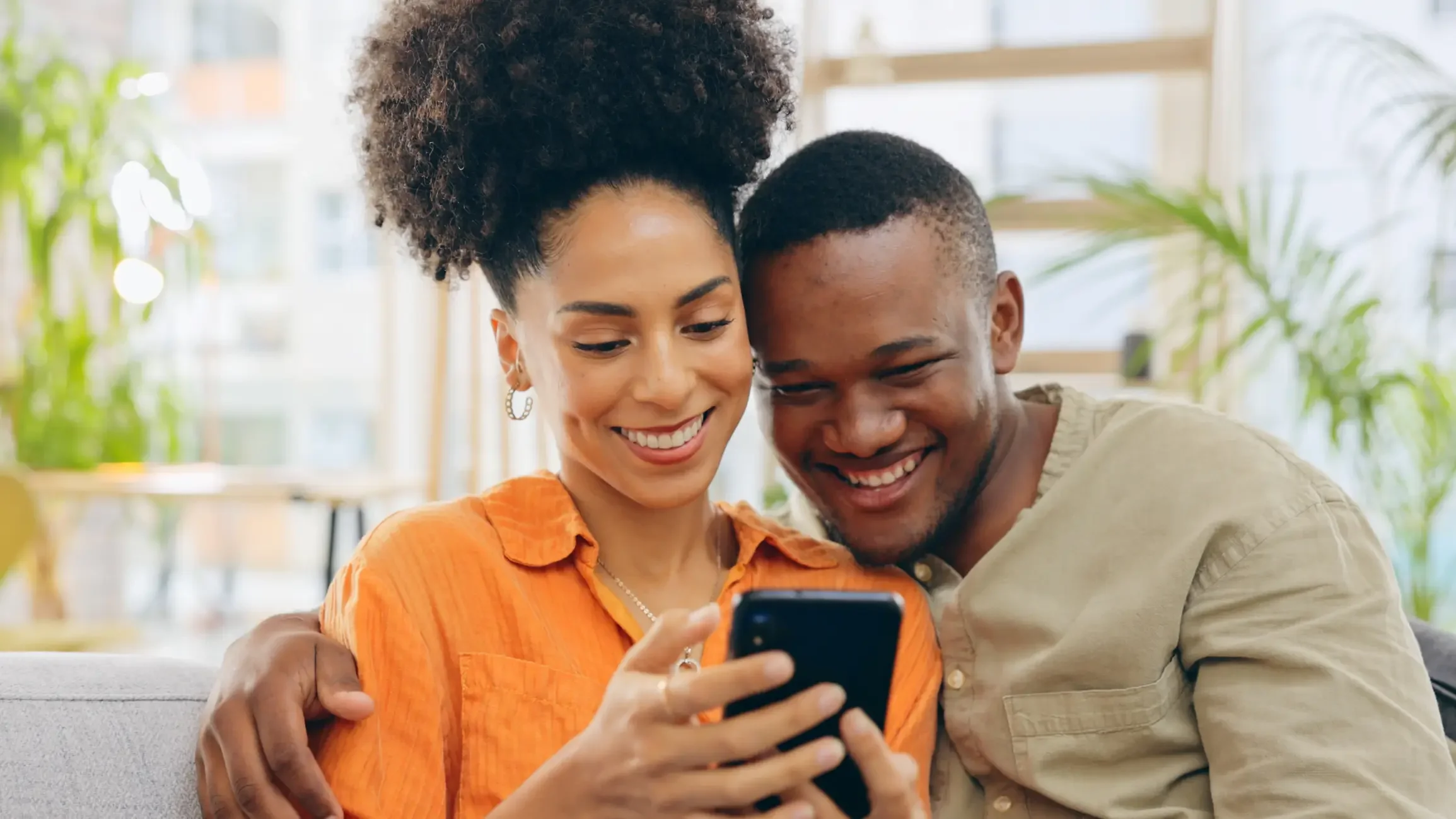 A smiling couple booking a consultation together on a phone