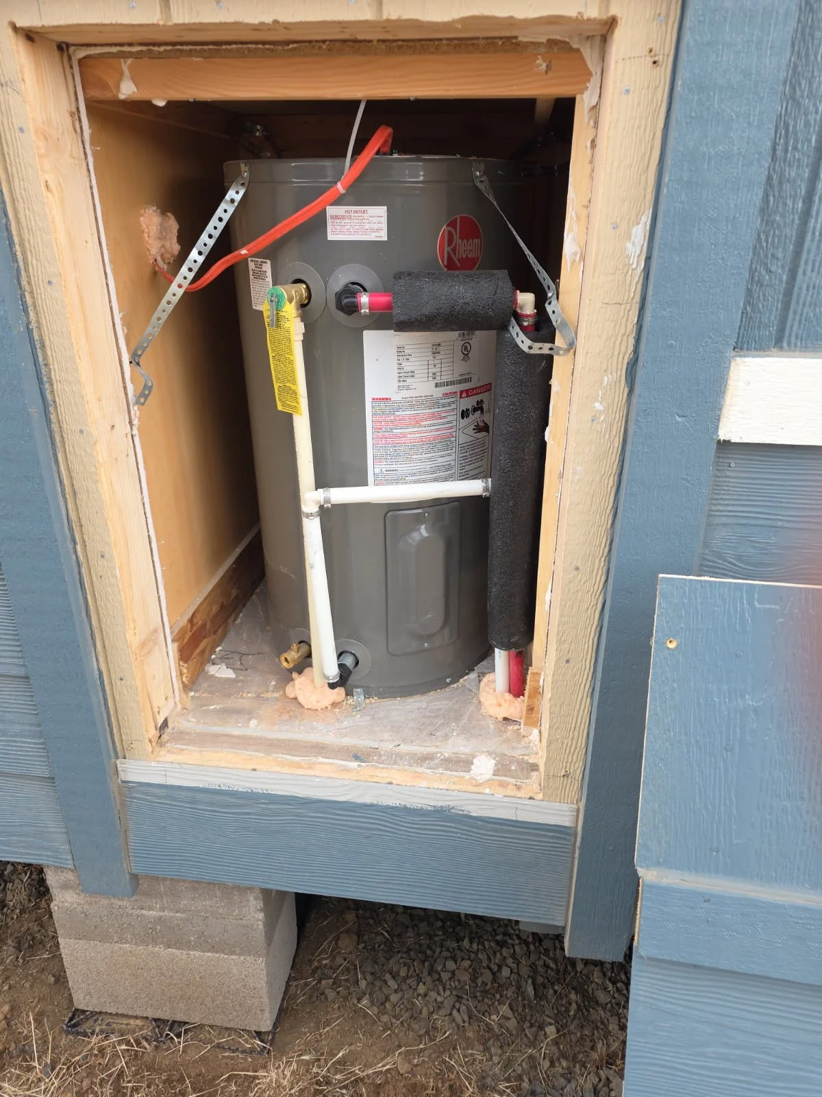 Water heater visible behind the opened exterior access panel of a park model tiny home
