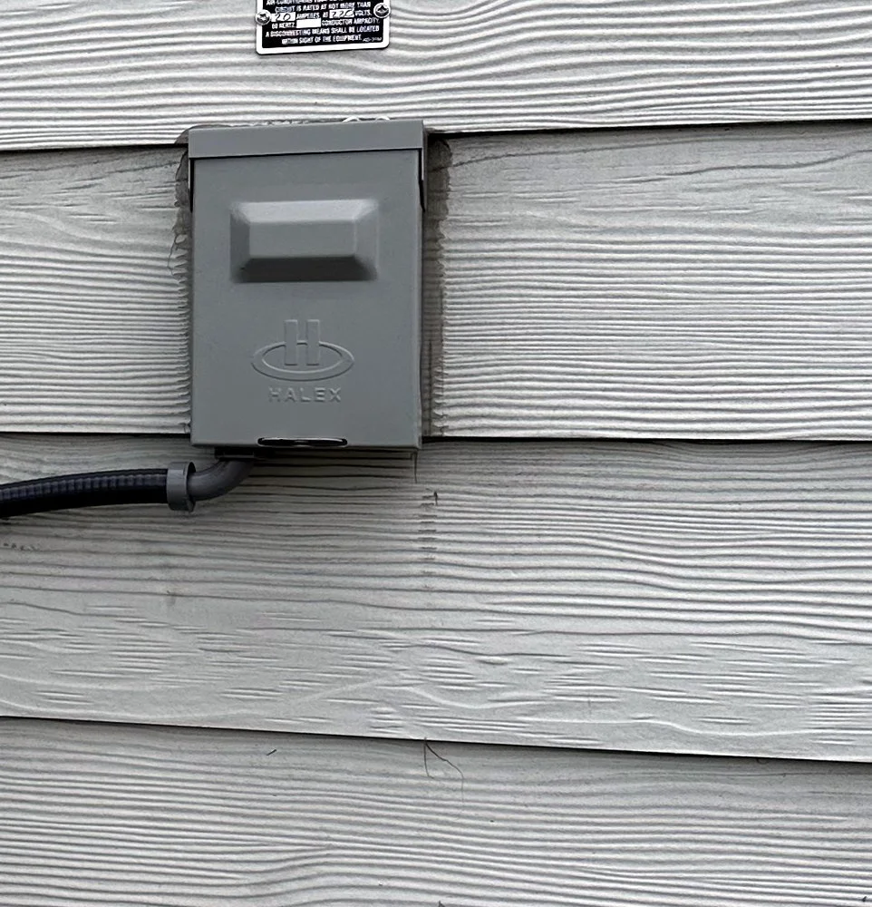 Gray 20 amp exterior electrical disconnect box wired and mounted on the tiny home wall, ready for a mini split