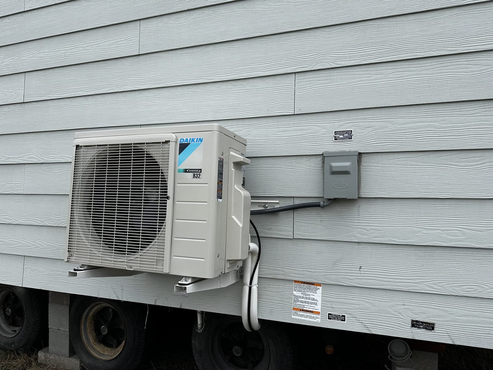 Daikin outdoor condenser unit and electrical disconnect mounted on the exterior wall of a park model tiny home