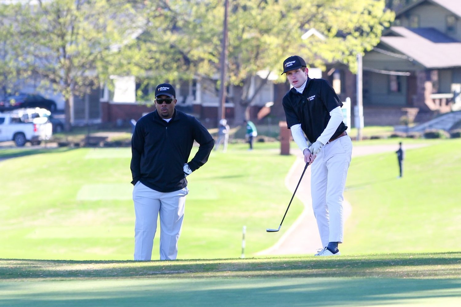 Two golfers lining up a chip shot