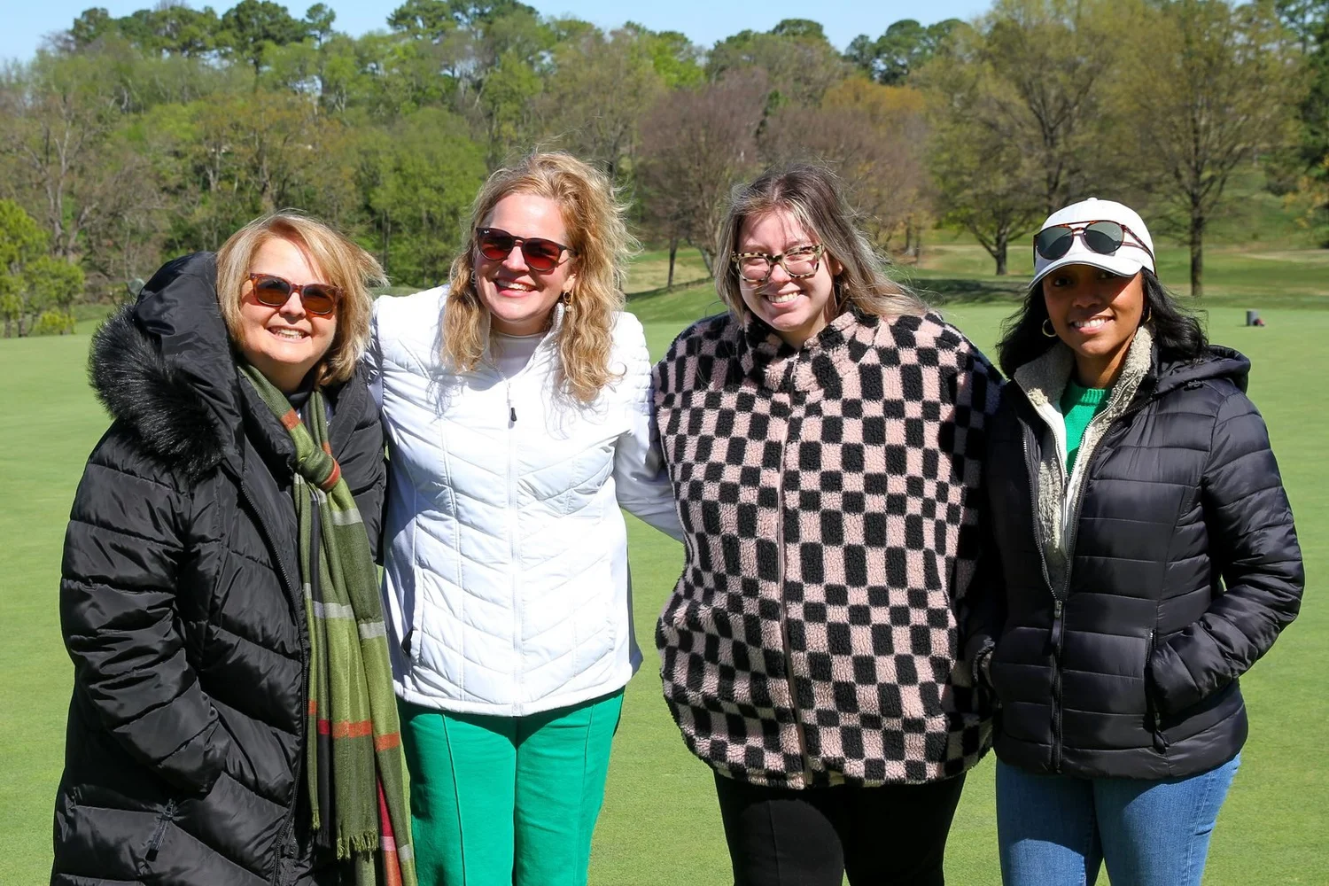 Four golfers smiling on the fairway